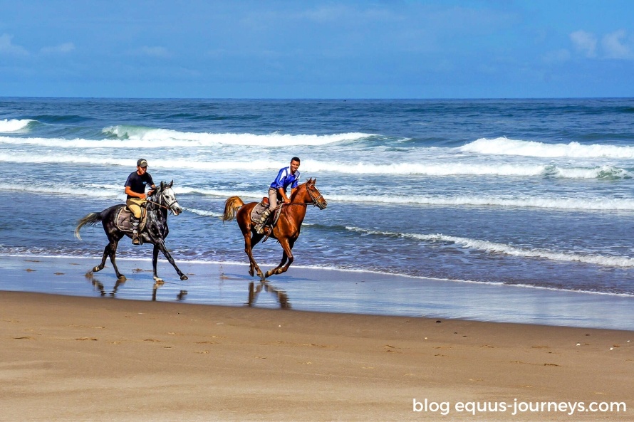 Two riders riding on a beach in Morocco
